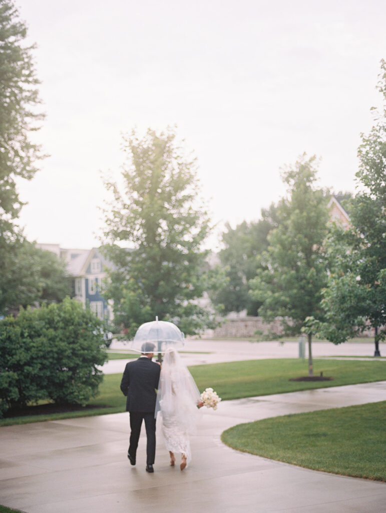 bride and groom walking with umbrella